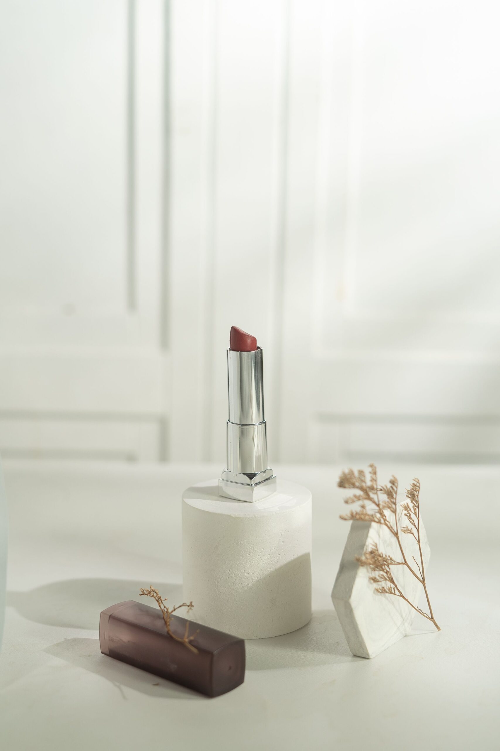 Elegant lipstick on a white surface with minimalist decor for a modern look.